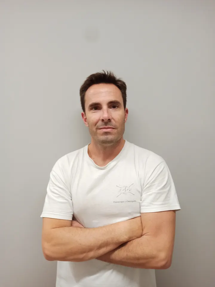 Arturo Brocate Aparicio, fisioterapeuta, con los brazos cruzados y la camiseta blanca con el logotipo de su consulta