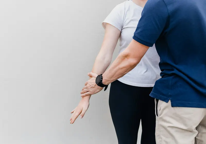 Un fisioterapeuta valora el movimiento del brazo de una paciente de pie